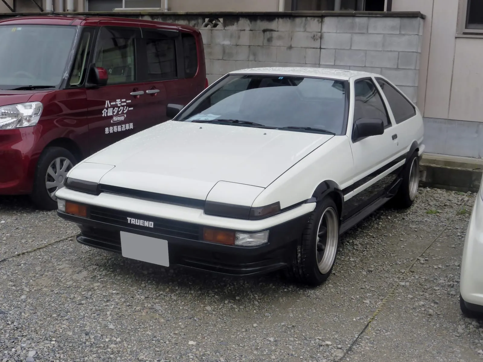 A white-and-black panda Toyota Sprinter Trueno AE86 parked in Japan