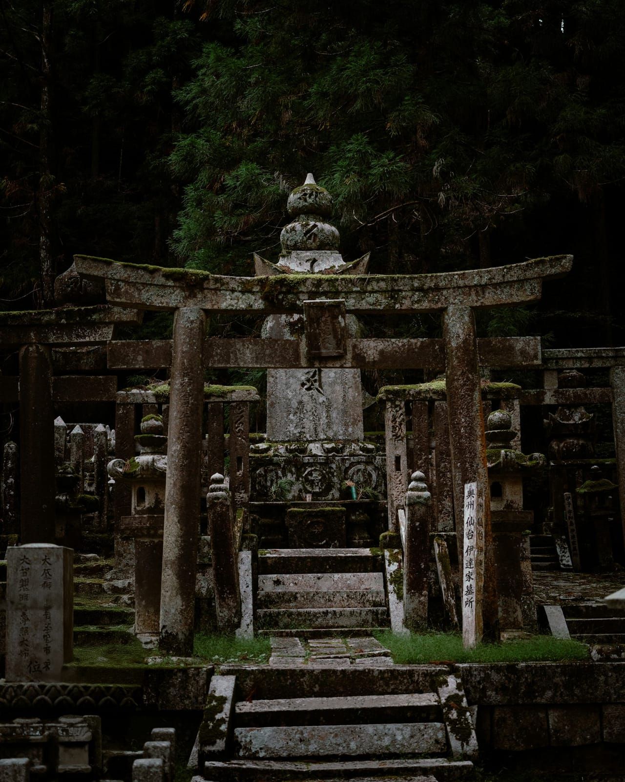 A stone statue among moss-covered graves in the Okunoin cemetery, Koyasan